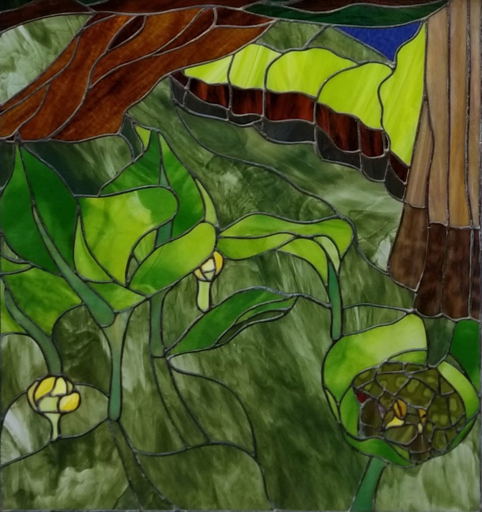 Art glass window with a turtle on a lily pad in the lower right-hand corner and a fallen tree in the upper right-hand corner