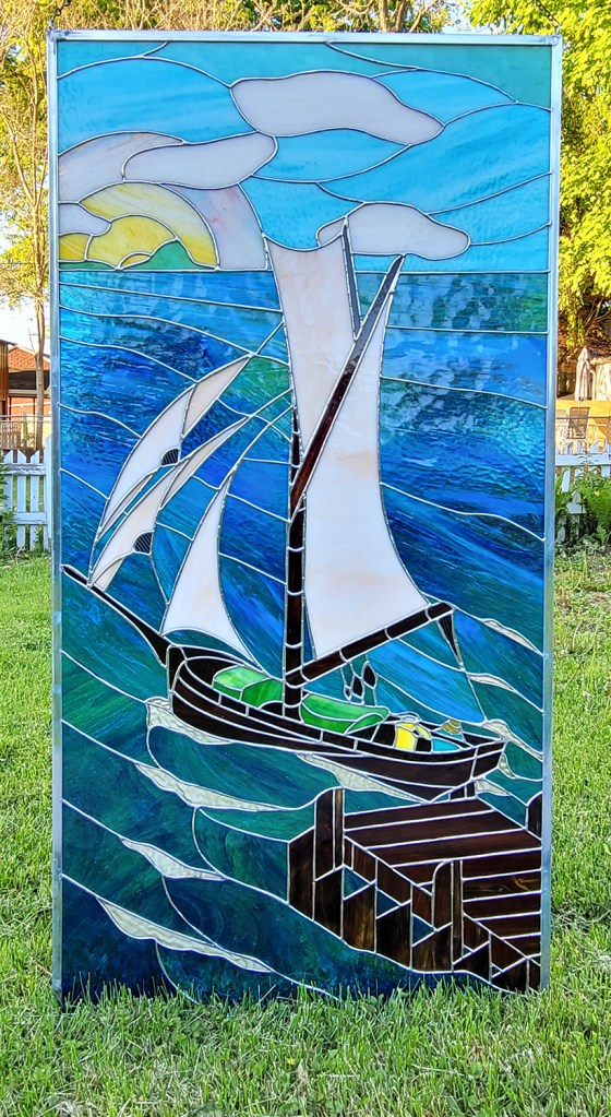 Aloha Calling, art glass window of a boat with two figures leaving a dock with the island of O'ahu in the distance.